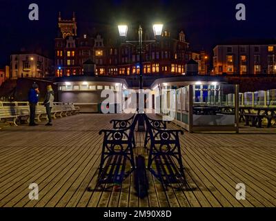 Am Kai in Richtung der Stadt Cromer in Nord-Norfolk bei Nacht an einem kalten Herbstabend mit einem warmen Licht von beleuchteten Gebäuden. Stockfoto