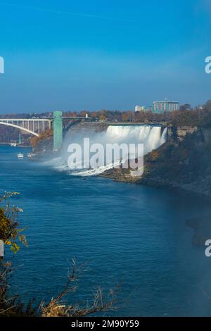 Ein vertikales Bild von den Niagarafällen und der Regenbogenbrücke unter dem blauen Himmel Stockfoto