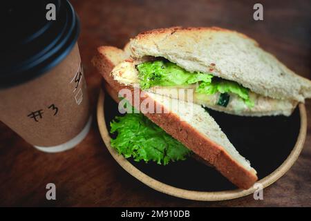 Ein kurzer Happen Sandwich mit Kaffee für den Start in den Tag. Stockfoto