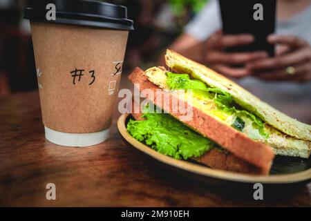 Ein kurzer Happen Sandwich mit Kaffee für den Start in den Tag. Stockfoto