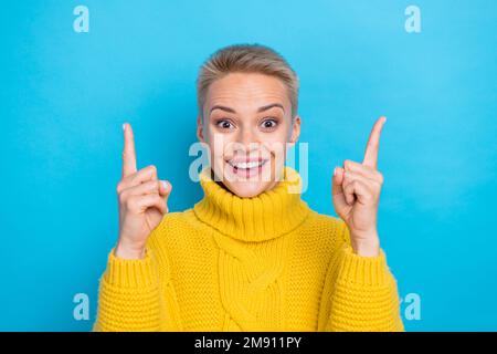 Foto einer überraschten Dame Tragen Sie kuschelige, warme gelbe, stilvolle Kleidung, die leer ist. Empfehlen Sie einen neuen Laden isoliert auf blauem Hintergrund Stockfoto