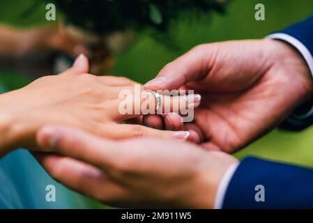 Der Bräutigam legt der Braut einen Ehering aus Gold an den Finger. Nahaufnahme von Handwechselringen Stockfoto