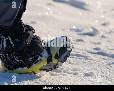 Nahaufnahme eines Mannes, der auf einem schneebedeckten Berg wandert, in Stiefeln mit Schuhpikes. Wanderung im Winter im Freien Stockfoto