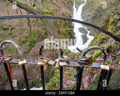 Als Geste der Liebe und des Engagements am Wasserfall Stock Ghyll in Ambleside, Lake District, Großbritannien, an einem Zaun angebrachte Vorhängeschlösser. Stockfoto