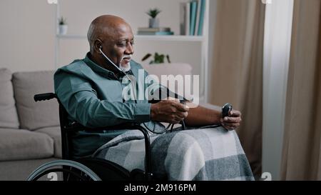 Seitenansicht afrikanischer alter 60s Mann krank Senior Rentner Glatzkopf mit grauem Bart Messung des Blutdrucks mit elektronischem medizinischem Gerät und Stethoskop Stockfoto