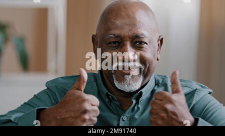Portrait eines glücklichen älteren afroamerikanischen Mannes, der lächelt, alte Senioren, die Daumen hoch, positiver Großvater, der auf die Kamera schaut und Handgesten zeigt Stockfoto