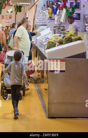 Teneriffa, Spanien - 16. Januar 2023: Männer und ein Junge, die auf dem städtischen Fischmarkt einkaufen, besucht von einem anderen Mann im Konzept der Gleichstellung von Männern Stockfoto