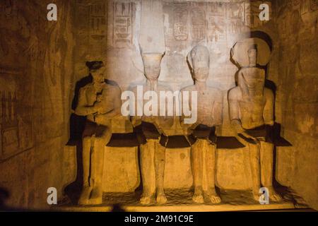 Statuen von Ptah, Amun Ra, König Ramesses II. Und Ra-Horakhty, beleuchtet von den Sonnenstrahlen im Großen Tempel von Ramesses II. In Abu Simbel, Ägypten Stockfoto