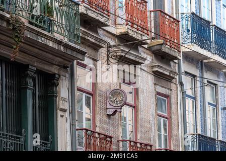 Alte, verfallene Uhr an der Wand auf einem Apartmentgebäude im klassischen portugiesischen Stil mit traditionellen Fliesen in Lissabon, Portugal Stockfoto