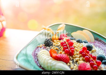 Acai Smoothie Schale mit Erdbeeren, Banane, Heidelbeeren, Apfel und Müsli im Sommer. Frühstücksschale mit Obst und Müsli, Nahaufnahme, Aufsatz Stockfoto