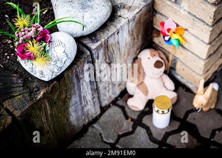 Barsinghausen, Deutschland. 16. Januar 2023. Blumen, zwei Plüschtiere und ein Windspiel liegen neben einer Grabkerze an einem Hauseingang in der Region Hannover. Nach dem Tod eines vierjährigen Jungen in Barsinghausen richten sich die Verdachtsmomente der Ermittler vor allem an den Partner der Mutter. Der Mann soll das Kind schwer missbraucht und verletzt haben, während die Mutter beschuldigt wird, ihrem Kind nicht zu helfen. Kredit: Moritz Frankenberg/dpa/Alamy Live News Stockfoto