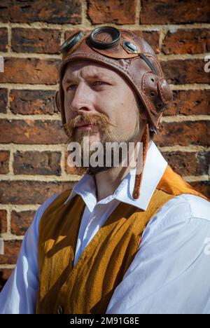 Porträt eines heldenhaft aussehenden Mannes mit Bart. Er trägt einen alten Flughelm. Steampunk-Pilot, Abenteurer, Entdecker. Stockfoto