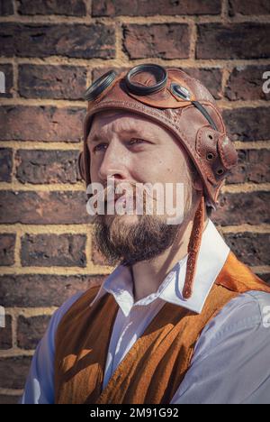 Porträt eines heldenhaft aussehenden Mannes mit Bart. Er trägt einen alten Flughelm. Steampunk-Pilot, Abenteurer, Entdecker. Stockfoto