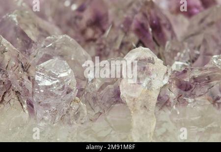 Helle, blassfarbene Amethyst-Quarz-Kristalle in Rohmineralform. Feine Details und Texturen bieten einen abstrakten Hintergrund. Stockfoto