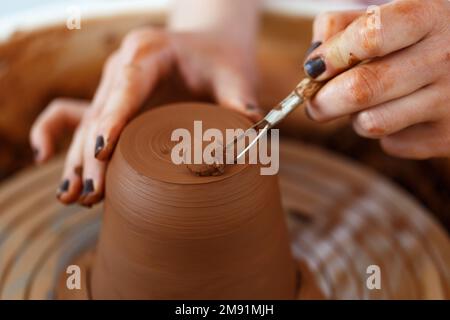 Weibliche Hände halten eine Schüssel zum Gießen von Tonprodukten. Formmethode zur Herstellung von Tonschalen. Handarbeit. Töpferei. Nahaufnahme. Töpferrad Stockfoto