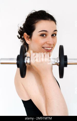 Junge, schöne, glückliche Frau, die zu Hause trainiert, mit einer Hantelglocke, die fit ist Stockfoto