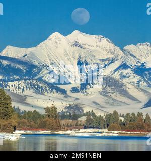 Der Vollmond erhebt sich im Winter über den Flathead River und die Mission Mountains in der Nähe von dixon, montana Stockfoto