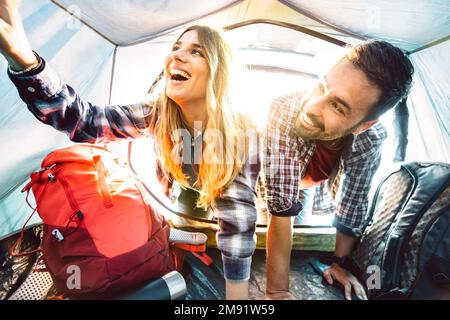 Ein Blick auf ein glückliches Paar im Campingzelt bei Sonnenuntergang - Abenteuer und Liebe Lebensstil Konzept auf Reisen - Junge Leute haben Spaß Stockfoto