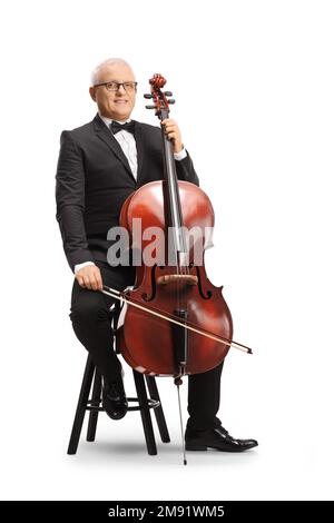 Langes Porträt eines Musikers in schwarzem Anzug und Fliege, der auf einem Stuhl mit Cello sitzt und isoliert auf weißem Hintergrund lächelt Stockfoto