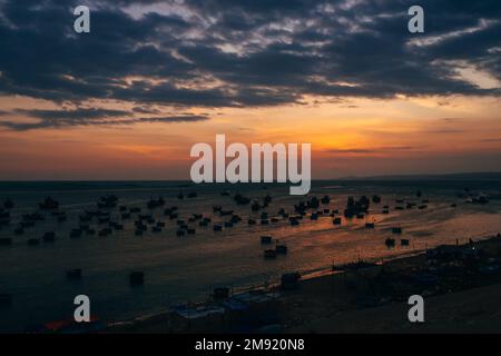 Silhouetten traditioneller vietnamesischer Boote im Fischerdorf Mui Ne bei Sonnenuntergang Stockfoto