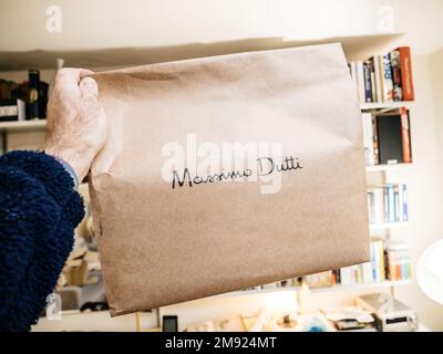 Paris, Frankreich - 2. Dez. 2022: POV-Paket für männliche Hand mit Massimo Dutti Modehändler-Logo - Auspacken modischer Kleidung, die online im Express-Online-Shop gekauft wurde. Lieferung innerhalb eines Tages. Stockfoto