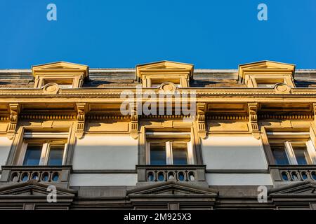 Nahaufnahme des oberen Teils eines eleganten, weißen Haussmann-Gebäudes mit Balkonen und blauem Himmel in Paris Stockfoto