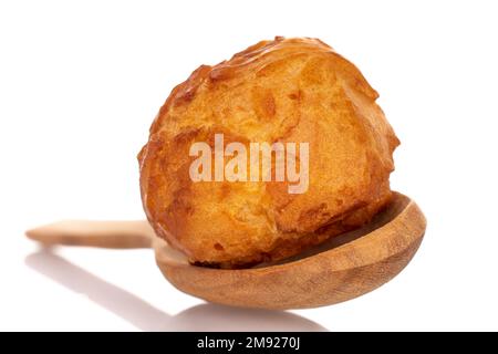 Mehrere süße Chouquettes mit einem Holzlöffel auf weißem Hintergrund. Stockfoto