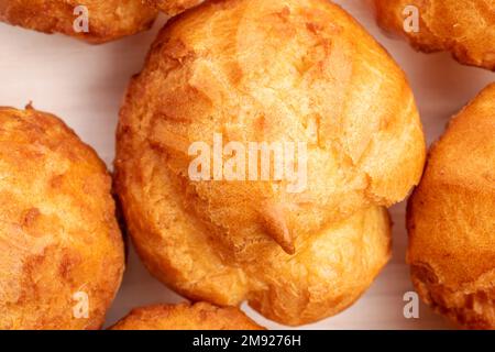 Mehrere frisch duftende Chouquettes auf einem Holztisch, Nahaufnahme, Draufsicht. Stockfoto