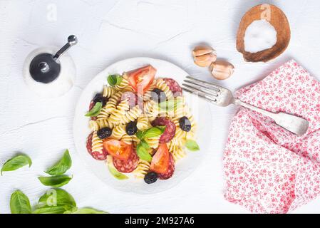 Antipasto-Salat mit Pasta, Tomaten, Oliven, roten Zwiebeln, Paprika, Salami Stockfoto