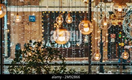 Abstrakter, verschwommener Hintergrund mit großem Panoramafenster. Festliche Innendekoration, Beleuchtung Girlanden, Lampen, Laternen Stockfoto