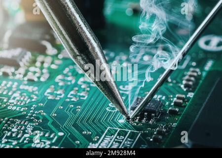 Lötkolben löten den Computerchip auf die Leiterplatte. Nahaufnahme Stockfoto