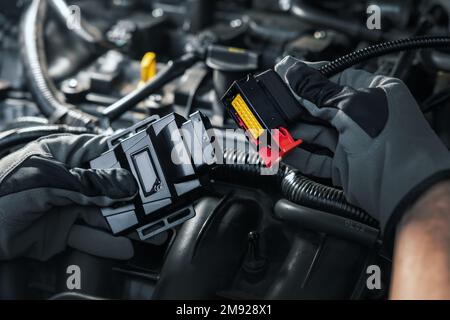 Mechaniker, der eine Chip-Tuning-Box am Automotor installiert Stockfoto