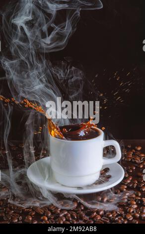 Eine vertikale Aufnahme einer Tasse, aus der Kaffeetropfen mit Bohnen auf dem Tisch auf dunklem Hintergrund gegossen werden Stockfoto