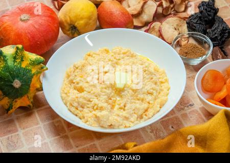 Kürbisbrei mit Hirse, Milch und Zimt. Nahaufnahme von Kürbisbrei mit Hirse, serviert in einer weißen Schüssel, selektiver Fokus, horizontaler Schuss. Stockfoto