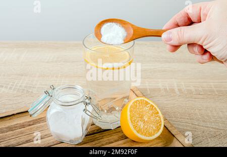 Nahaufnahme der Frau Hand Gießen Backnatron in Trinkglas mit Wasser und Zitronensaft, gesundheitliche Vorteile für das Verdauungssystem Konzept. Stockfoto