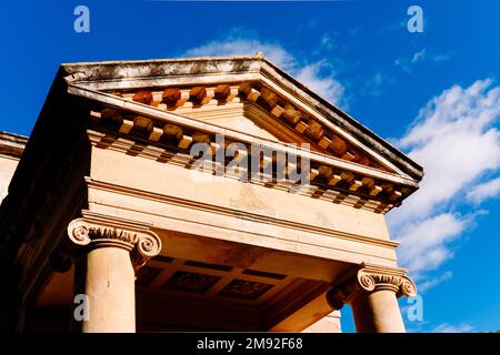 Ein Säulenabschnitt mit Säulen und einem dreieckigen Fußbogen auf der griechischen Fassade eines Tempels. Stockfoto