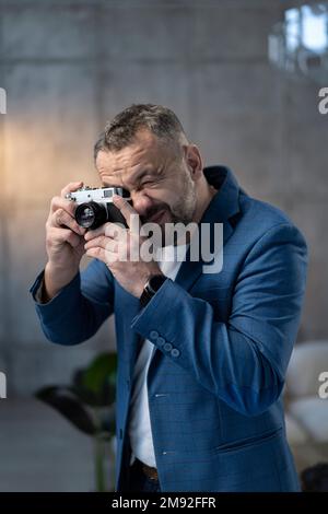 Ein junger Mann, der draußen mit einer alten Kamera fotografiert Stockfoto