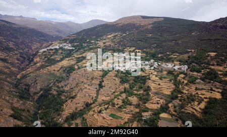 Luftaufnahme des Dorfes Capileira mit der Sierra Nevada im Hintergrund. Ländlicher Tourismus und wunderschöne Bergziele. Stockfoto