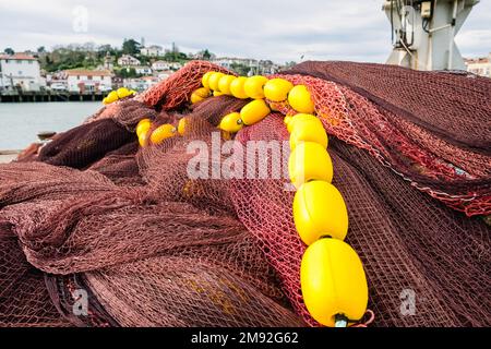 Töpfe, Netze und Fischerboote in einem kantabrischen Hafen. Stockfoto