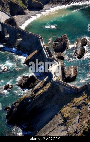 Blick nach unten von San Juan de Gaztelugatxe - Blick nach unten über die Küstenfelsen und Verbindung von San Juan de Gaztelugatxe, Bucht von biskaya, Spanien. Smaragd Stockfoto