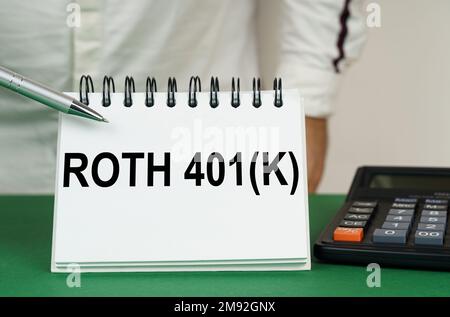 Geschäftskonzept. Auf einer grünen Oberfläche befindet sich ein Taschenrechner, und ein Mann zeigt mit einem Stift auf ein Notizbuch mit der Aufschrift Roth 401k Stockfoto