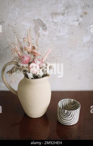 Minimalistische Zusammensetzung getrockneter Blüten in Keramikvase als Heimdekoration. Stockfoto