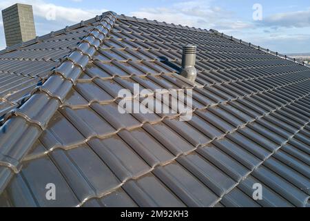 Verschlüsse von Lüftungsrohren auf dem Hausdach mit Keramikschindeln bedeckt. Geflieste Gebäudeabdeckung Stockfoto