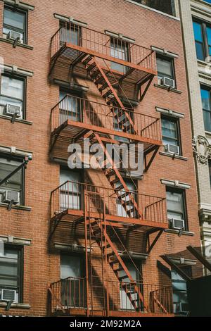 Von unten sehen Sie das alte New Yorker Backsteingebäude mit einer Feuertreppe im Freien in den USA Stockfoto