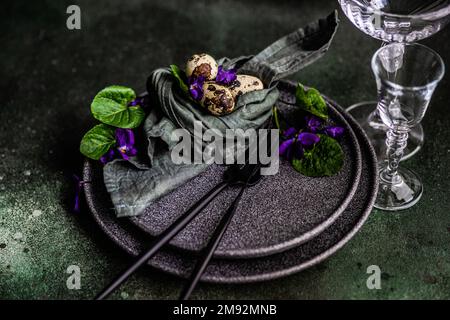 Frühlingstisch mit wilder blauer Veilchenblume auf schwarzem Teller Stockfoto