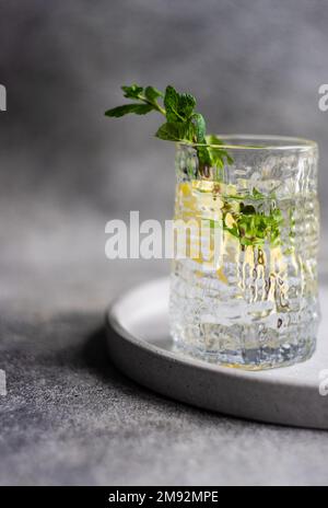 Ein Glas reines Morgenwasser mit Zitrone und frischer Minze auf dem Tisch Stockfoto