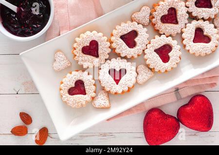 Valentinstag Marmeladen Kekse mit Herzformen. Blick von oben auf Servierteller mit weißem Holzhintergrund Stockfoto