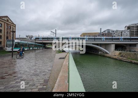 Ourcq Kanal. Blick auf den Kanal, einen Zug auf einer Brücke, eine Straßenbahn und einen Radfahrer Stockfoto