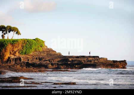 Junge Männer und Frauen, die an einem malerischen Ort in Bali, Indonesien, Handys in der Hand halten. Stockfoto