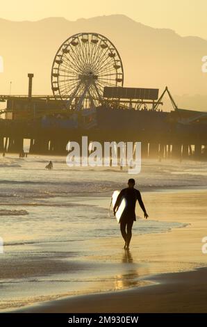 Surfer mit Surfbrett am Pier am Santa Monica Beach in Los Angeles, CA, USA Stockfoto